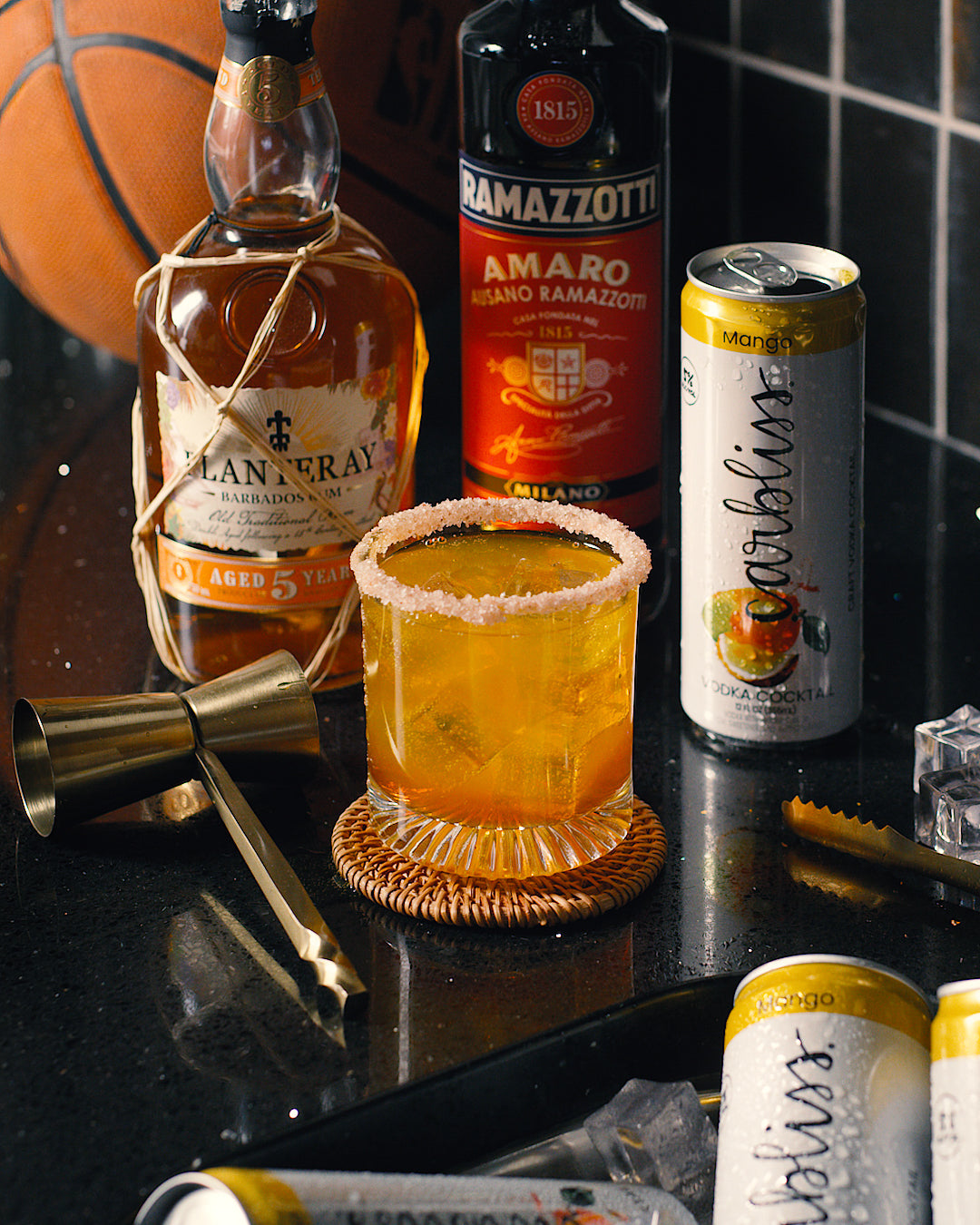 Beverage setup with a cocktail, bottles, and a can on a reflective surface.
